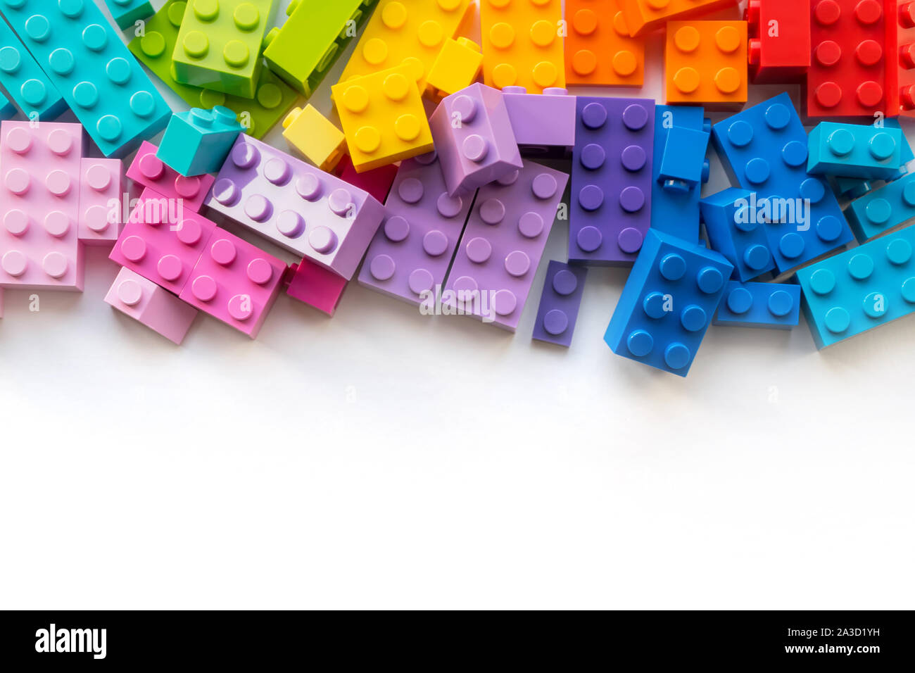Un sacco di colorati costruttore Plastick blocchi su sfondo bianco. Giochi diffusi. Copyspace Foto Stock