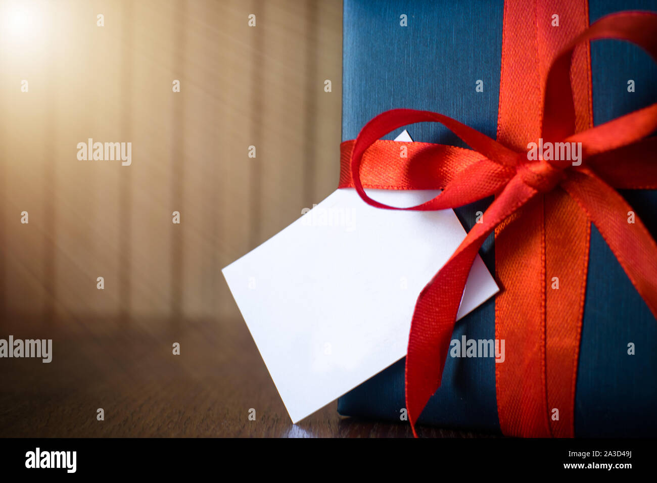 Giornata dei padri. Pacchetto regalo avvolto con carta blu e corda con un nastro rosso su sfondo di legno. Copyspace Foto Stock