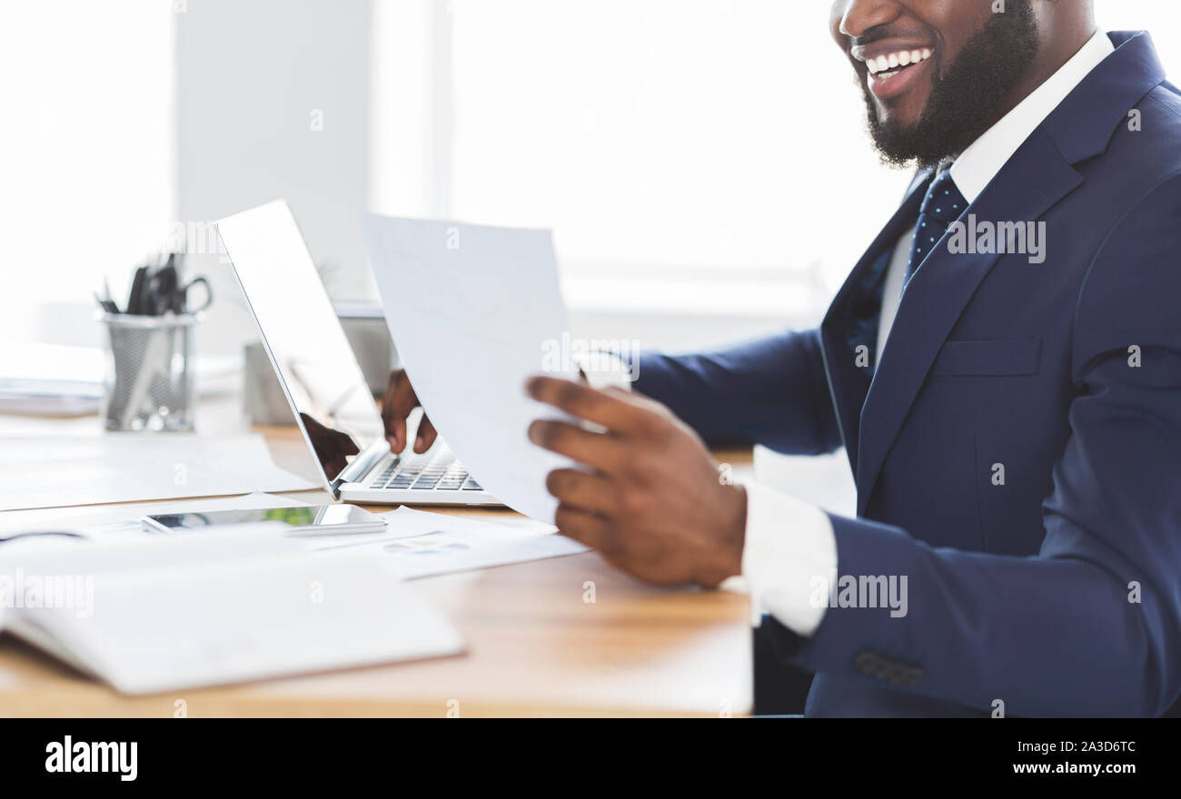Foto ritagliata di felice imprenditore africano alla ricerca di documenti Foto Stock
