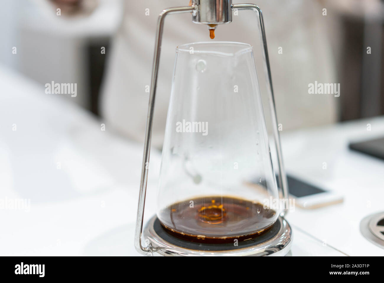 Processo di preparazione di caffè nero in chemex versare il caffè in luminoso moderno cafe'. Modi alternativi per preparare il caffè. Foto Stock