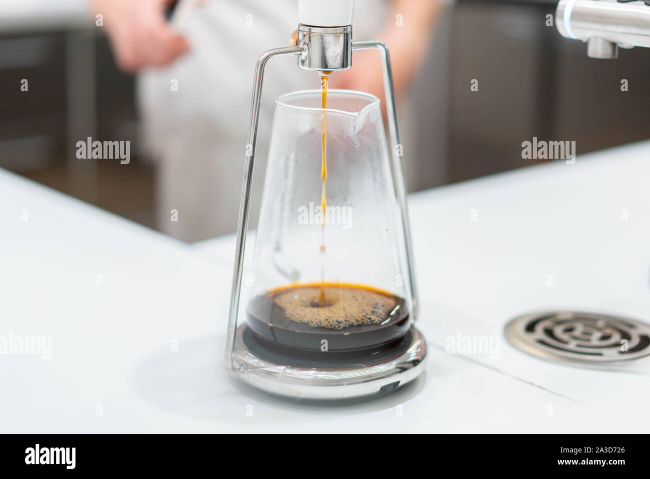 Processo di preparazione di caffè nero in chemex versare il caffè in luminoso moderno cafe'. Modi alternativi per preparare il caffè. Foto Stock