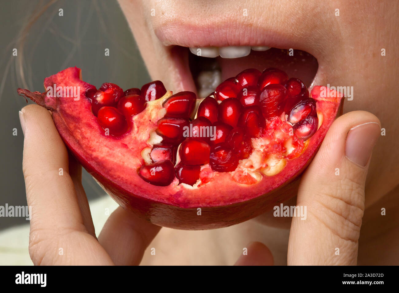 Donna di mangiare una parte del frutto di melograno, primo piano Foto Stock