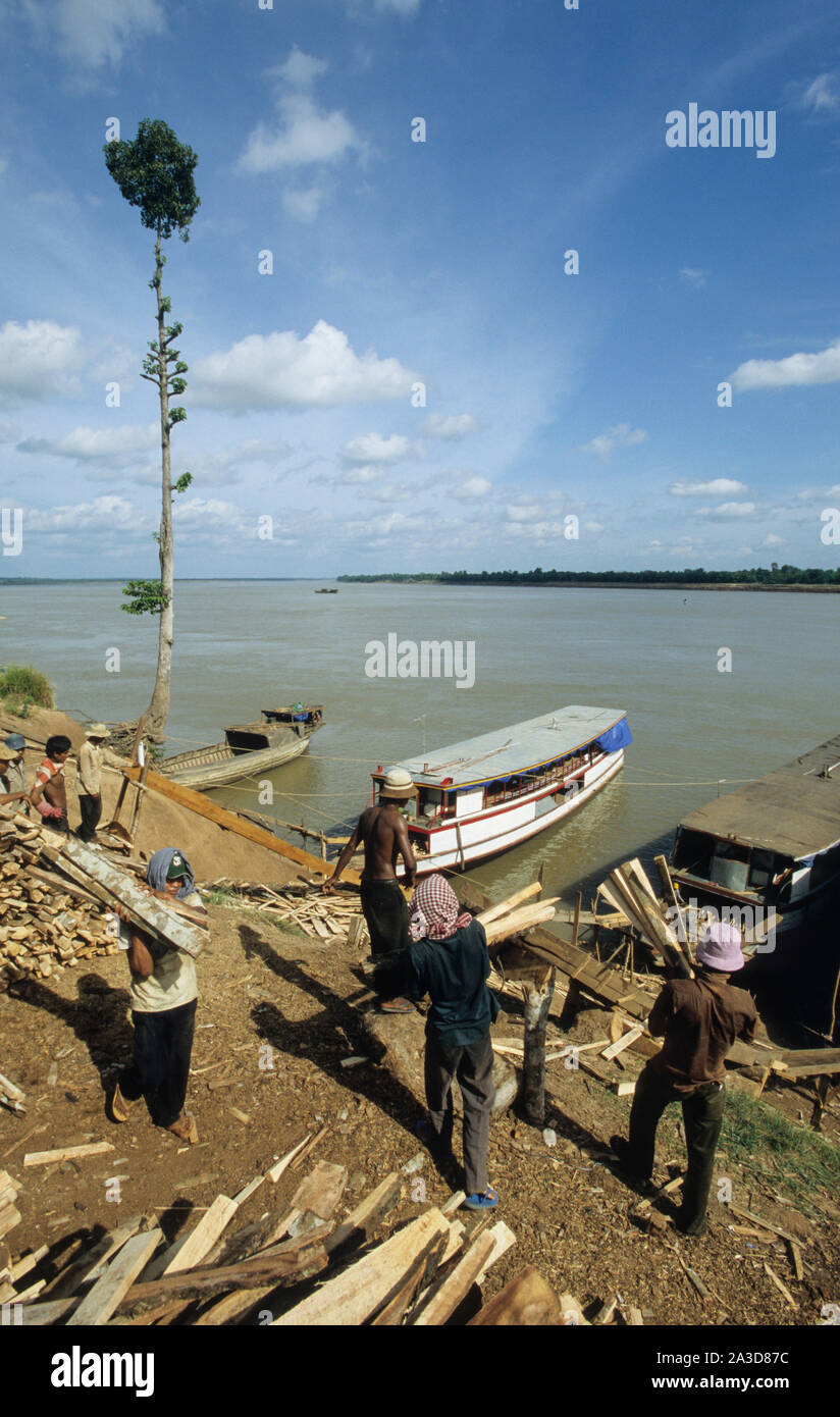 La Cambogia, il fiume Mekong, Kratie, la registrazione della foresta, il caricamento del legname sul fiume Mekong barche dalla rampa di scorrimento Foto Stock