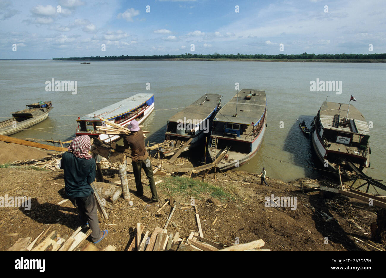 La Cambogia, il fiume Mekong, Kratie, la registrazione della foresta, il caricamento del legname sul fiume Mekong barche dalla rampa di scorrimento Foto Stock