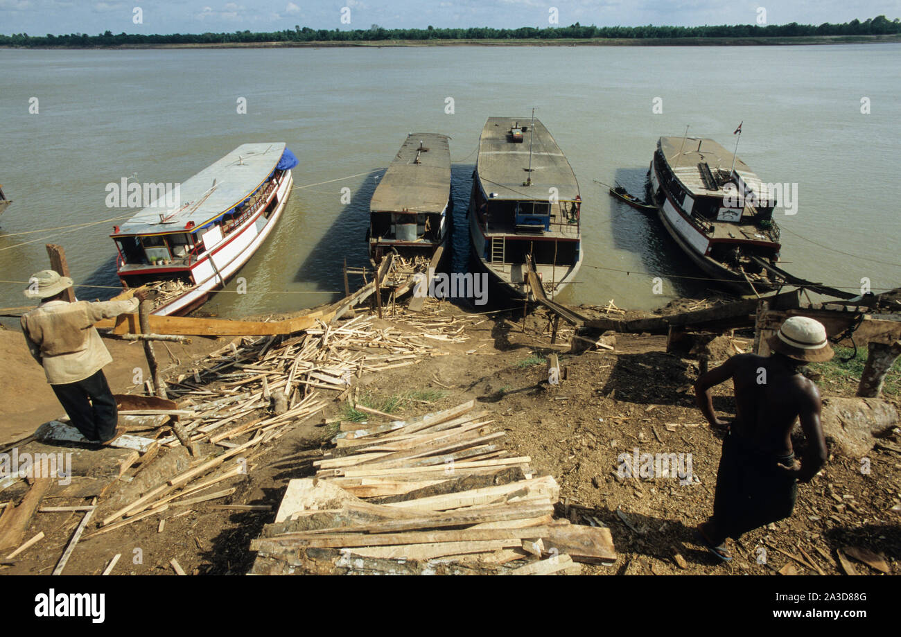 La Cambogia, il fiume Mekong, Kratie, la registrazione della foresta, il caricamento del legname sul fiume Mekong barche dalla rampa di scorrimento Foto Stock