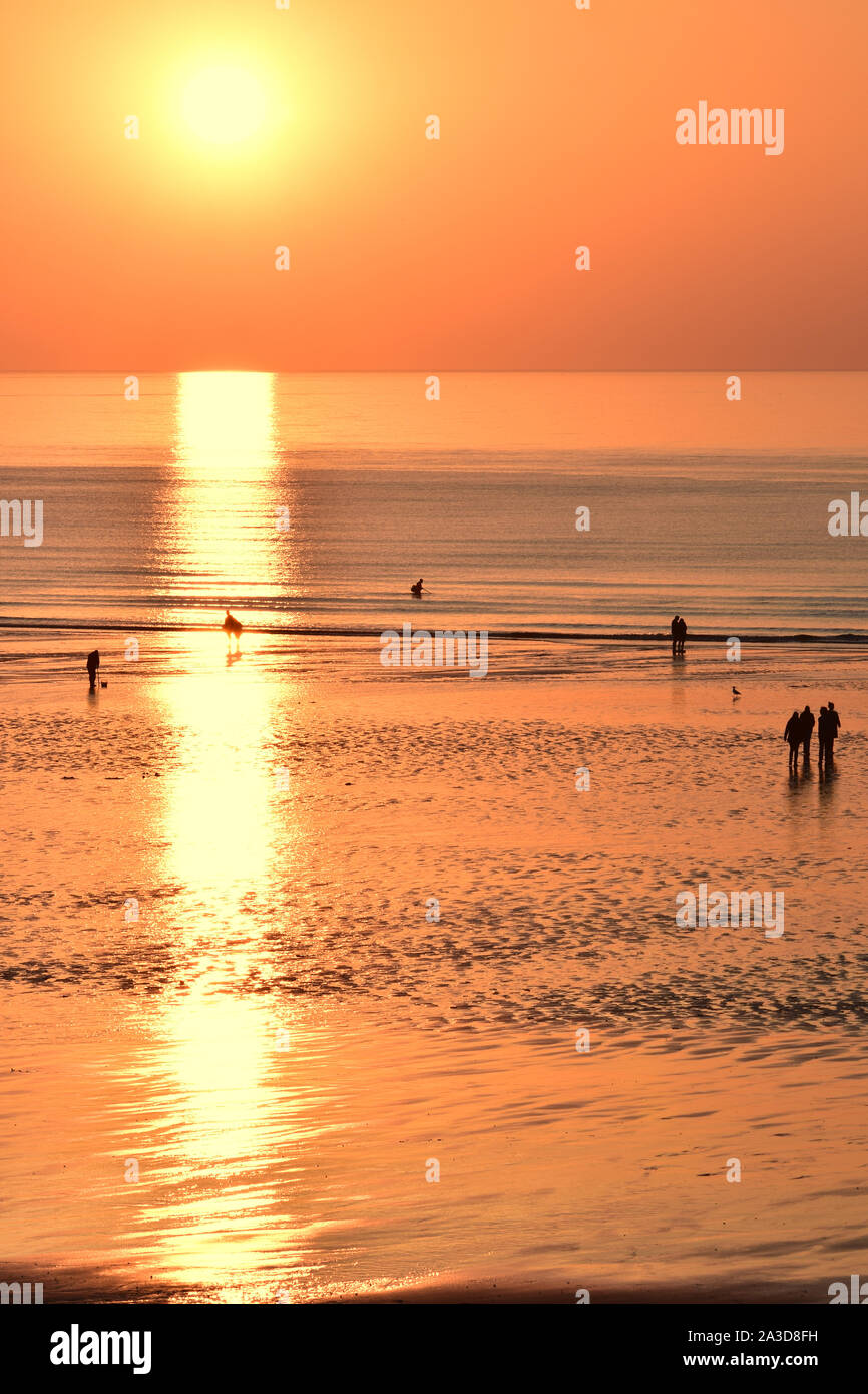 Plage de Ault Onival crépuscule au soleil couchant, à l'orizzonte sur une mer d'huile à marée basse. promeneurs et pêcheurs sur la plage. Foto Stock