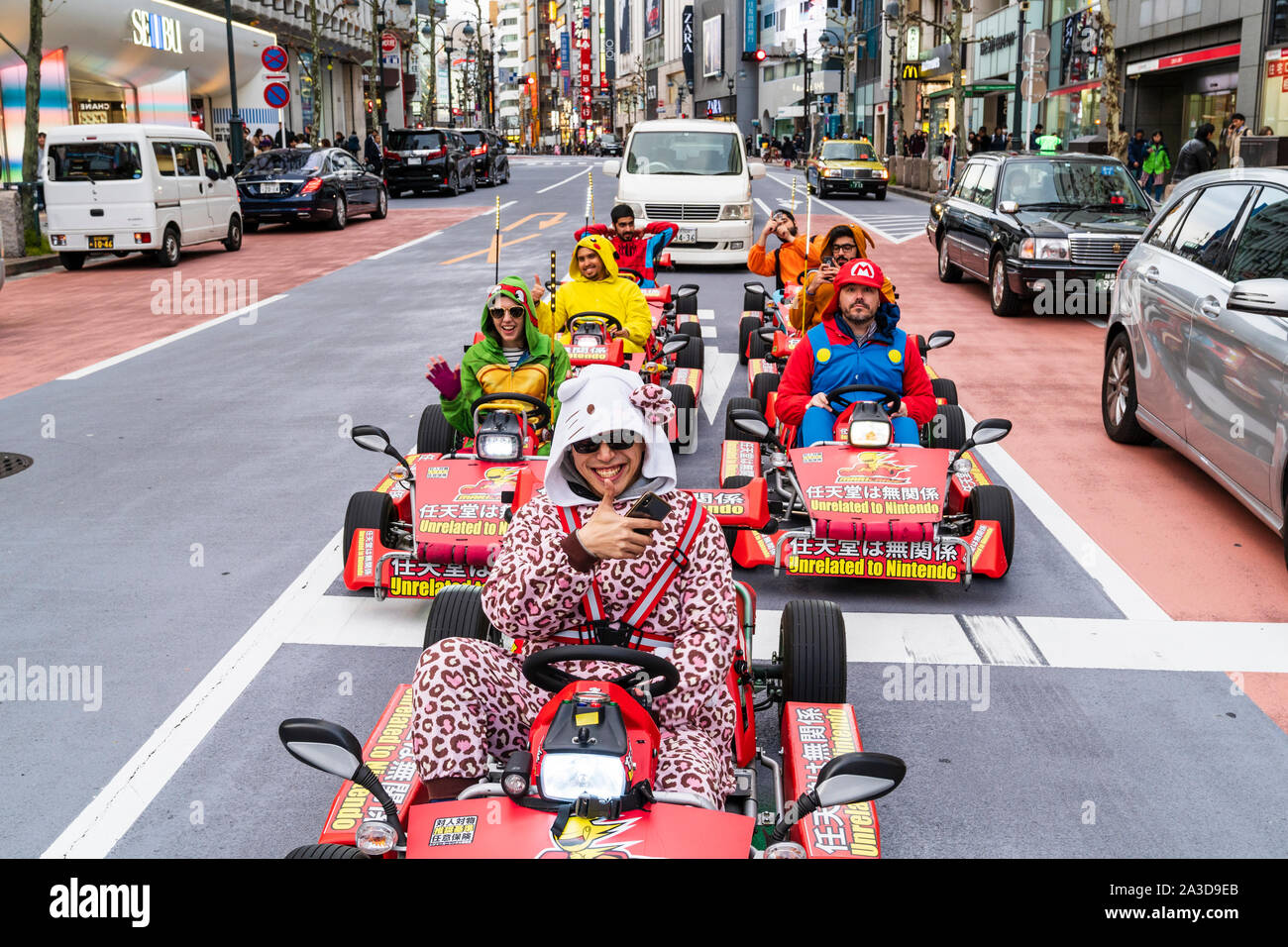 Tokyo, Shibuya crossing. Andare karting Mario Kart con driver vestiti come  i loro personaggi preferiti in attesa al bivio. Rivolta verso il  visualizzatore. Contatto visivo Foto stock - Alamy