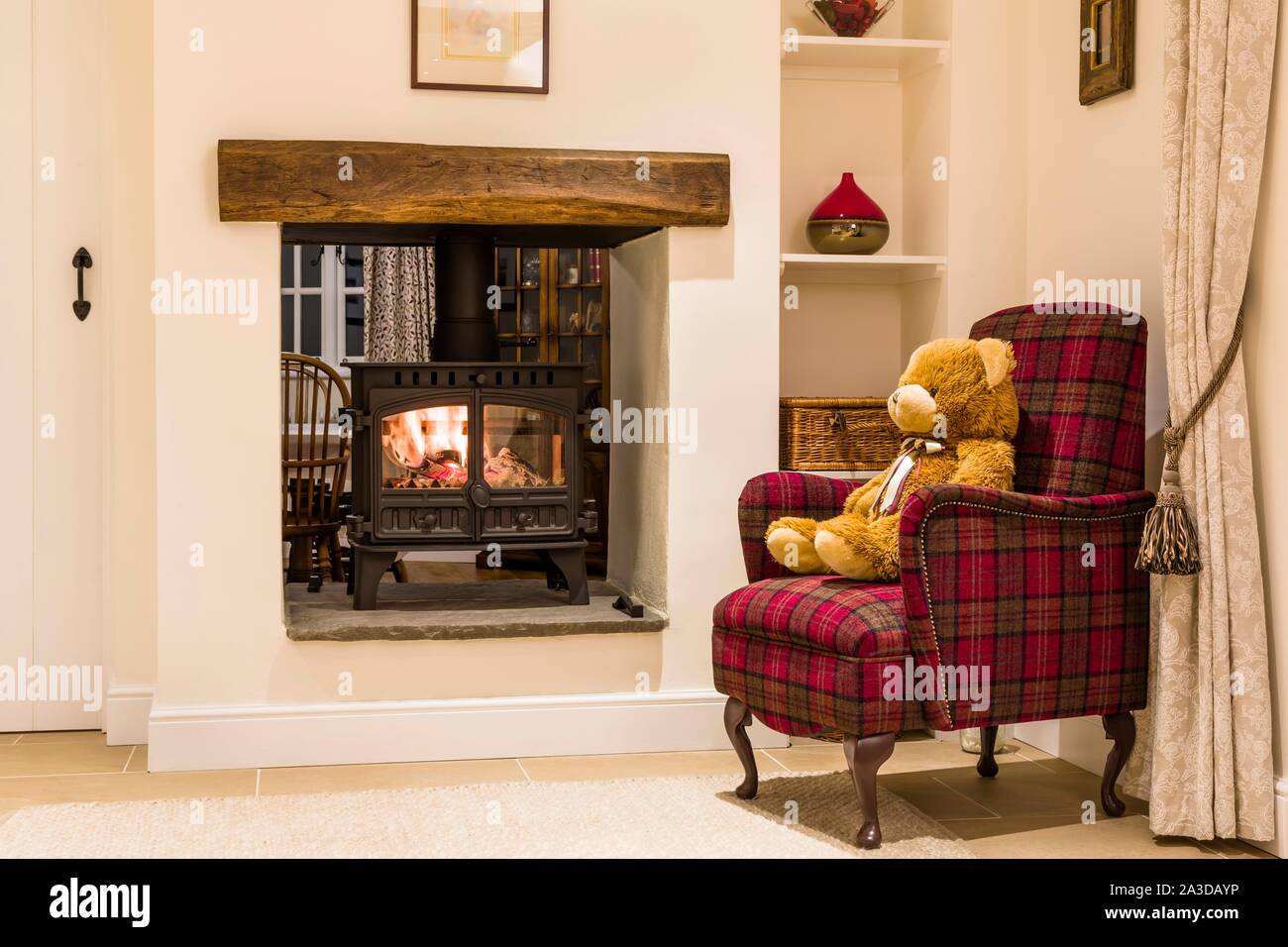 Un accogliente caminetto con stufa a legna e Teddy bear in un salotto home interno, REGNO UNITO Foto Stock