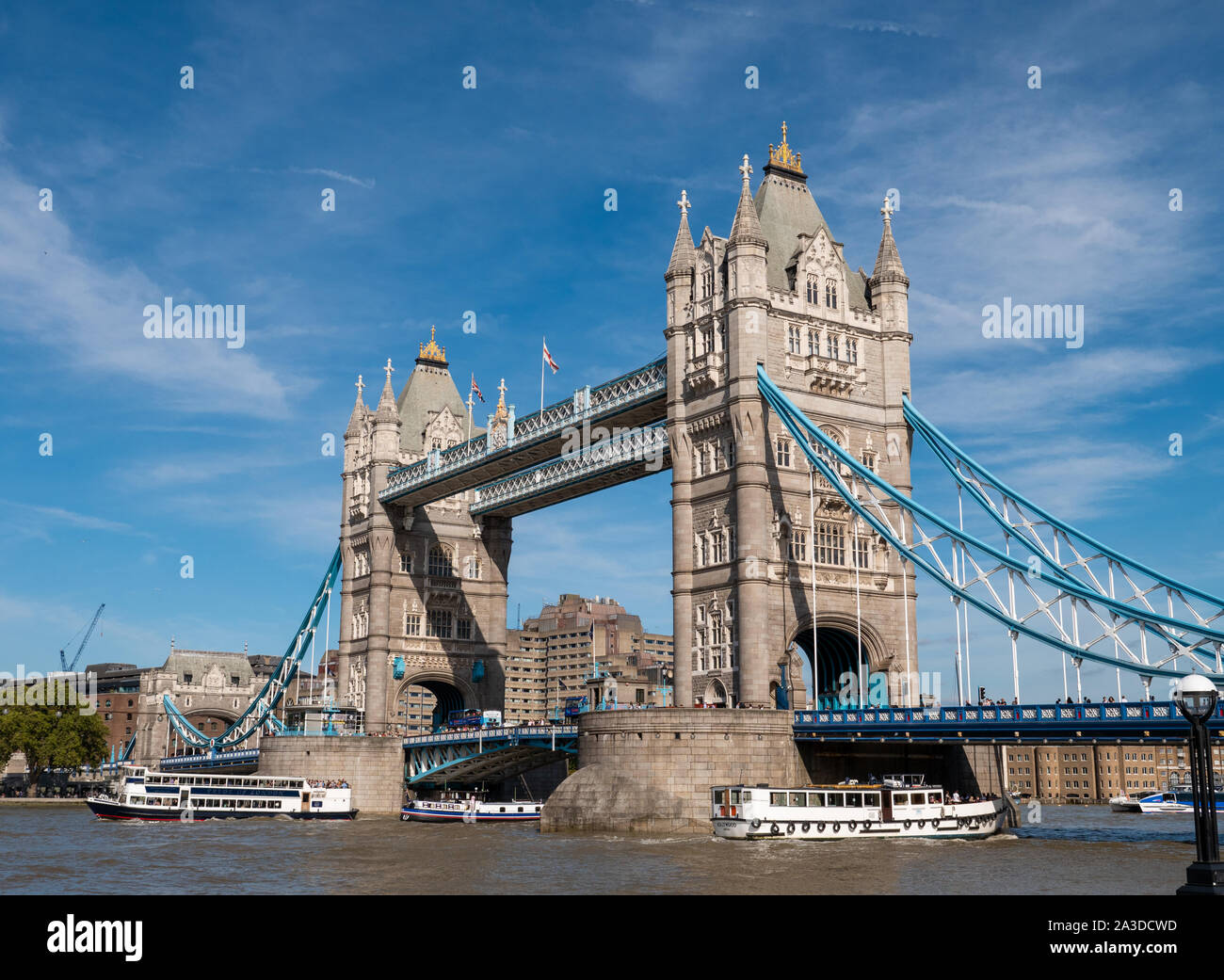 Barche sul fiume Tamigi passando sotto il Tower Bridge di Londra, Regno Unito Foto Stock