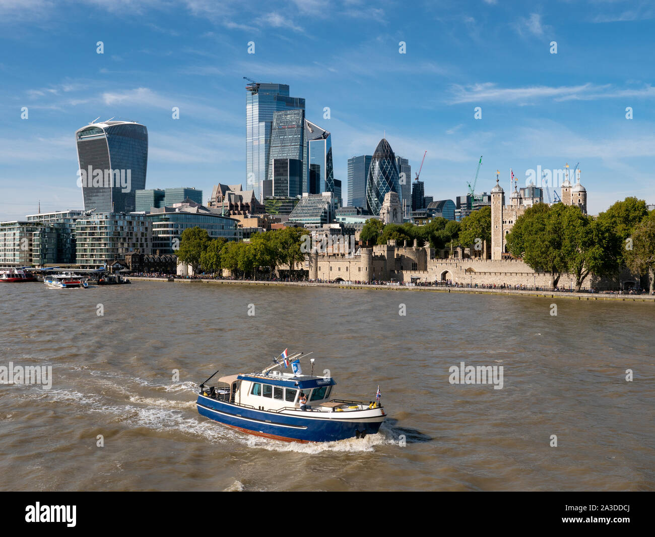 Piccola barca sul fiume Tamigi con la City di Londra grattacieli dietro, London, Regno Unito Foto Stock