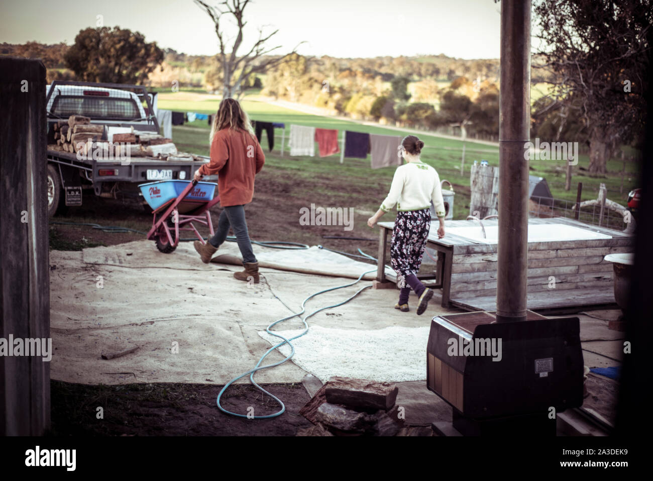 Coppia giovane su fattoria raccogliere legna dal retro del carrello al crepuscolo Foto Stock