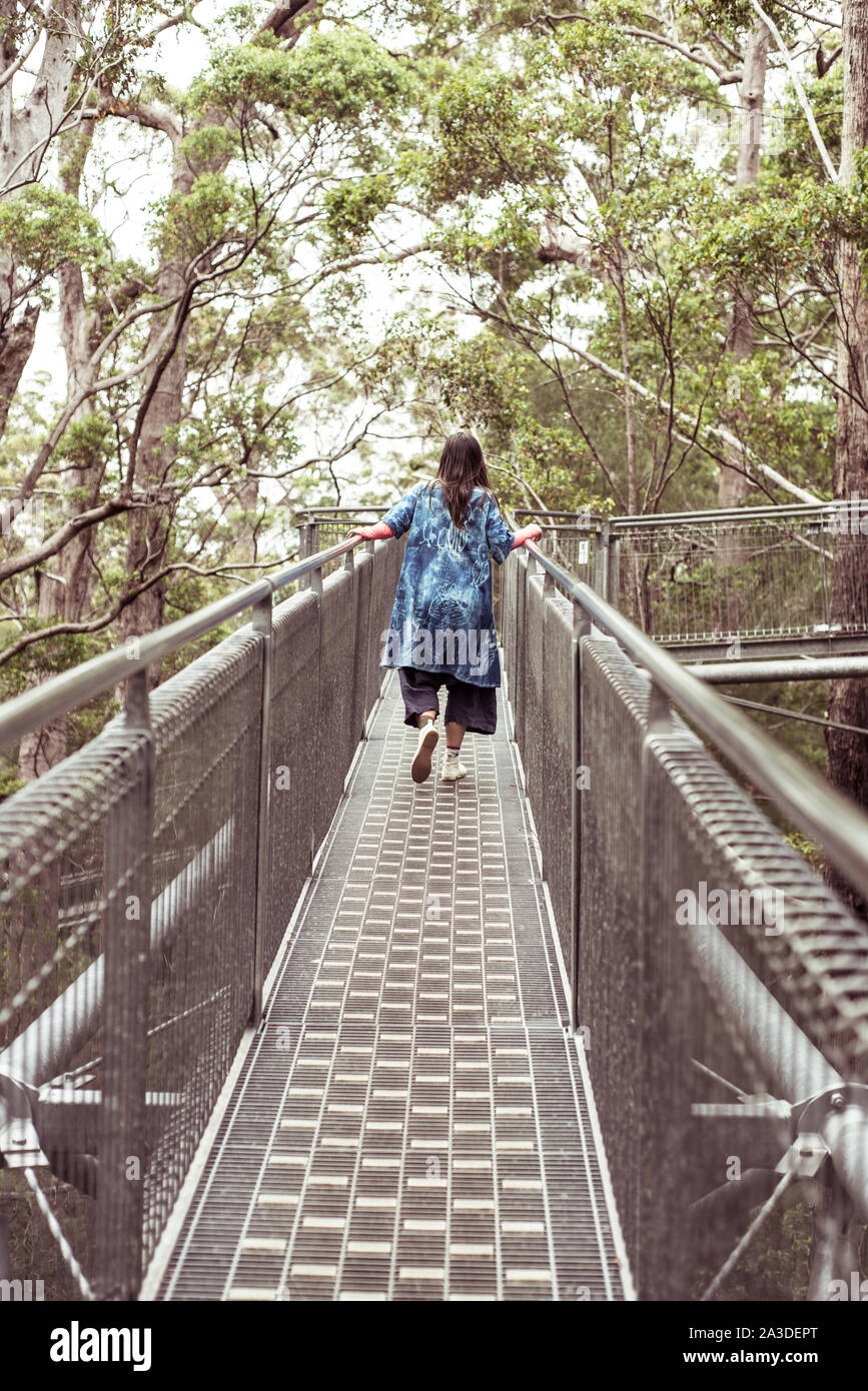 Donna in grande vestito blu si arrampica lungo il Tree Top Walk in remote australia Foto Stock