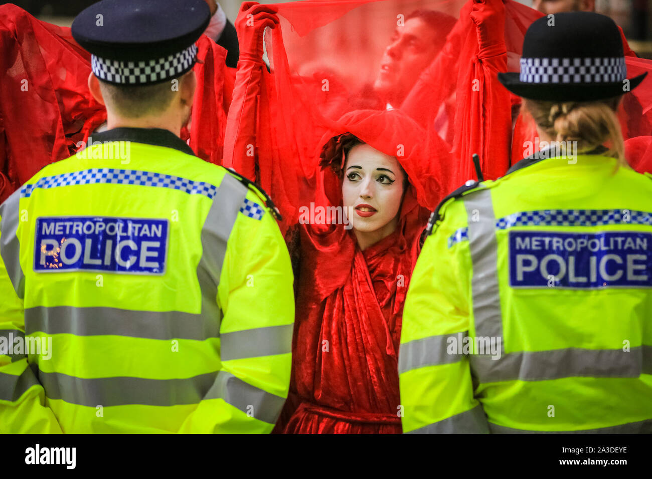 Londra, UK, 07 ott 2019. Estinzione della ribellione attivisti del gruppo "Brigate Rosse', con oltre un centinaio di partecipanti, confrontarsi con una linea di polizia a Millbank in Westminster, a muovere lentamente lungo la loro linea e guardando direttamente a funzionari, uno per uno. Credito: Imageplotter/Alamy Live News Foto Stock