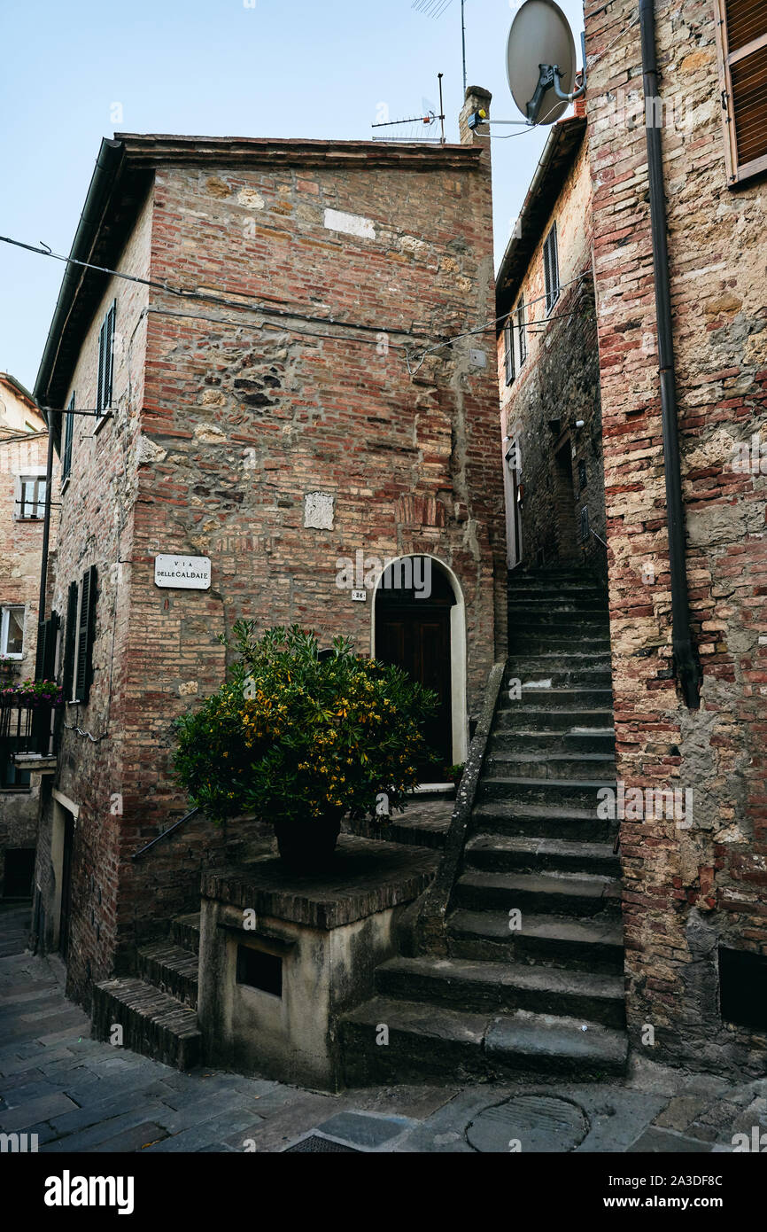 Tipiche italiane lane con l'annata di pareti in mattoni di edifici residenziali piccolo mandarino albero nel centro di stretta scalinata in pietra che conduce fino Foto Stock