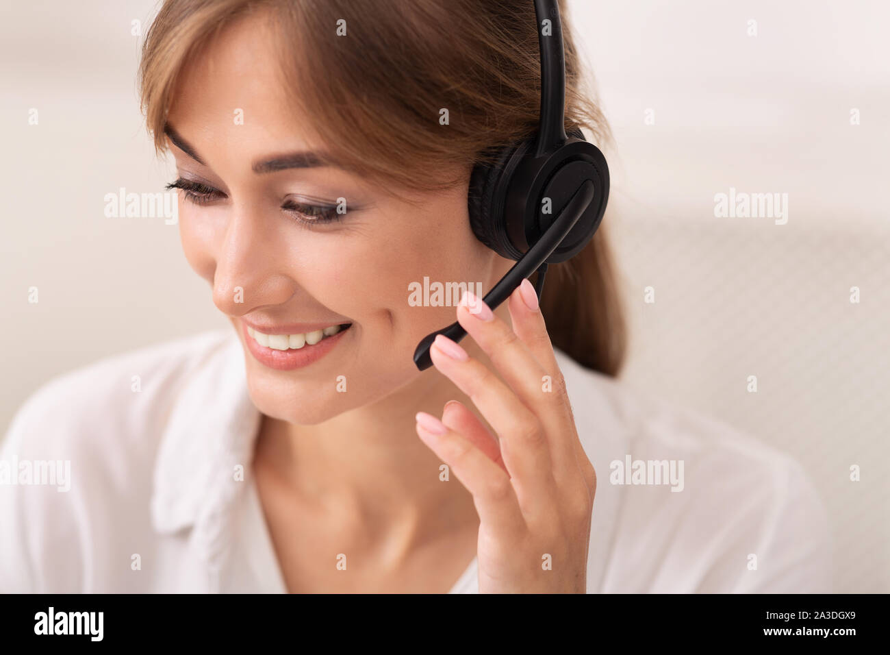 Signora positivo in cuffia lavorano nei call center, sfondo bianco Foto Stock