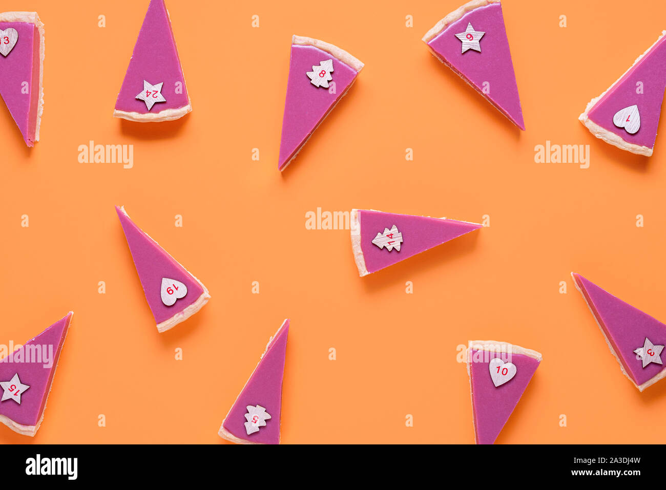 Fette di torta con i numeri per il calendario dell'Avvento. Il cioccolato rosa fette di torta pattern su sfondo arancione. Avvento natale. Ruby torta al cioccolato sullo sfondo Foto Stock