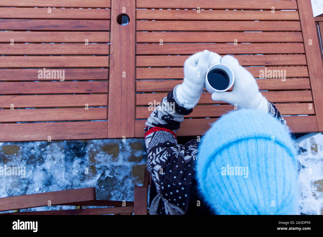 Vista dall'alto di una ragazza con una tazza di caffè caldo in muffole Foto Stock