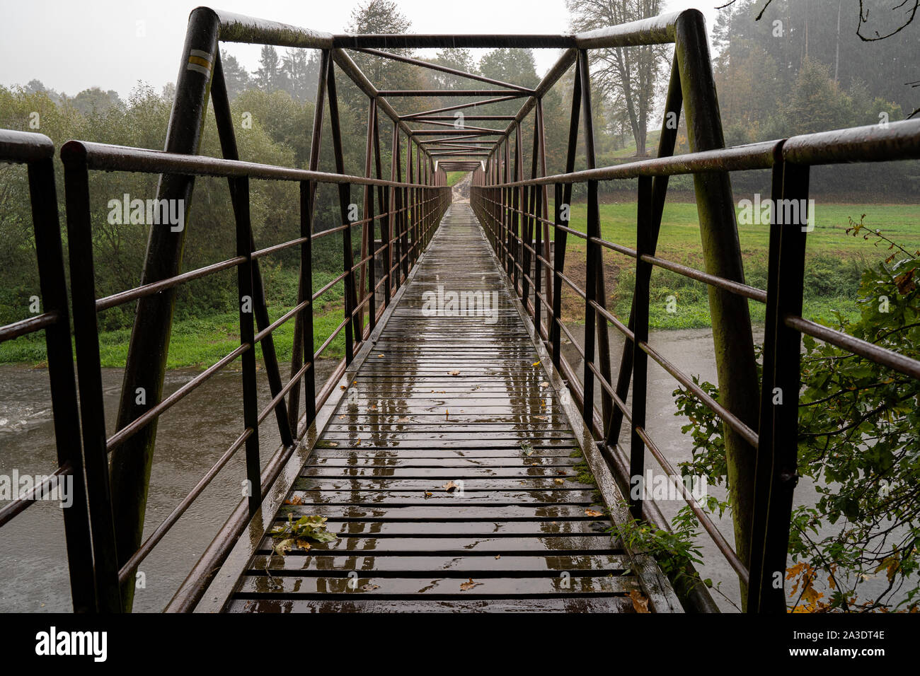 Ponte in acciaio con walkpath in legno. Varcando il fiume in cattive condizioni atmosferiche. Foto Stock