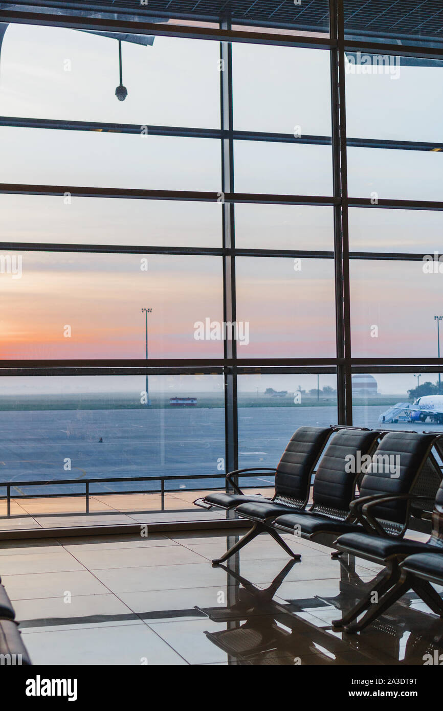 Vista di aeroporto interoir, banco vuoto sedie nella sala partenze durante il sunrise. Aeroplano e costruzione di sfondo. Viaggi e trasporti concetto Foto Stock