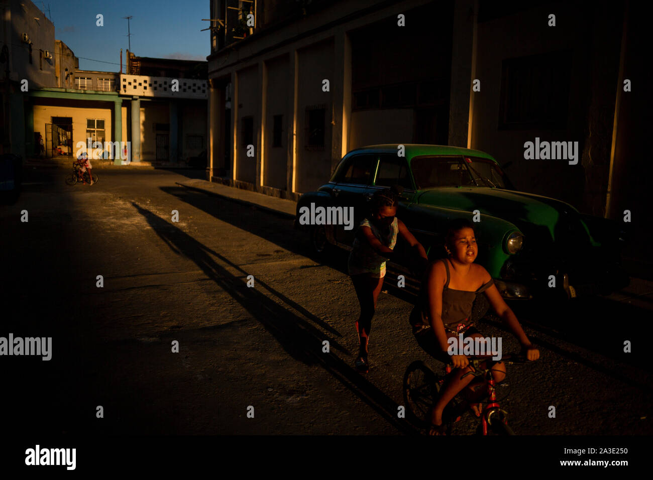 I bambini andare in bicicletta per le strade di La Habana durante il tramonto. Foto Stock