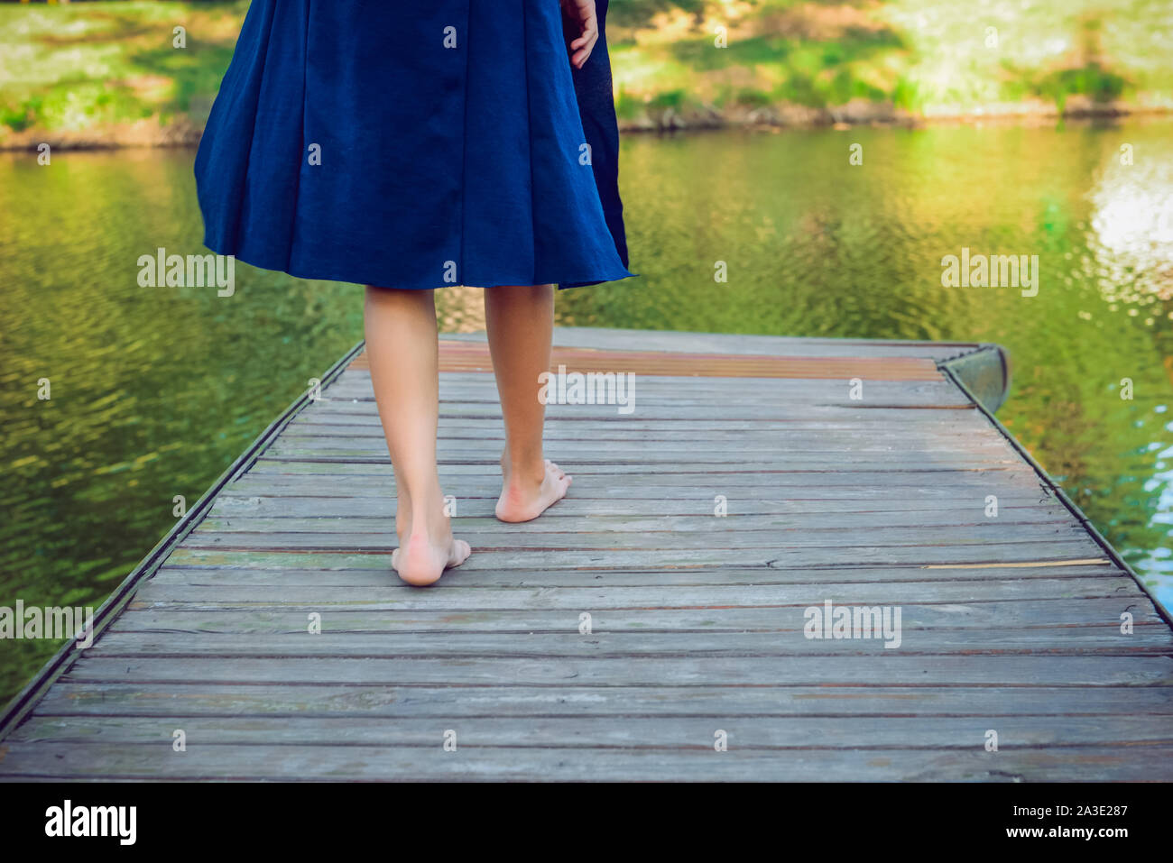 Giovane donna facendo un passo bootlessly sul molo in legno e lo spostamento in avanti per l'acqua, il nuovo concetto di opportunità. messa a fuoco selettiva Foto Stock