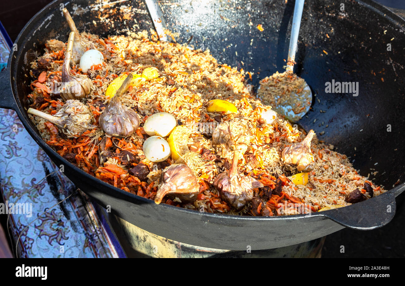 Tradizionale appetitosi Uzbek pilaf con verdure in un gran calderone all'aperto Foto Stock