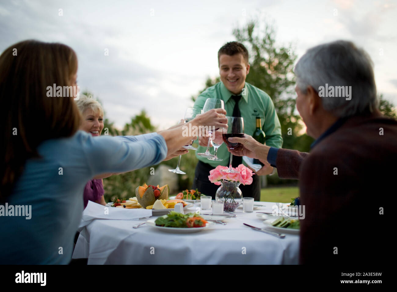 I giovani adulti cameriere tostare con adulto patroni. Foto Stock