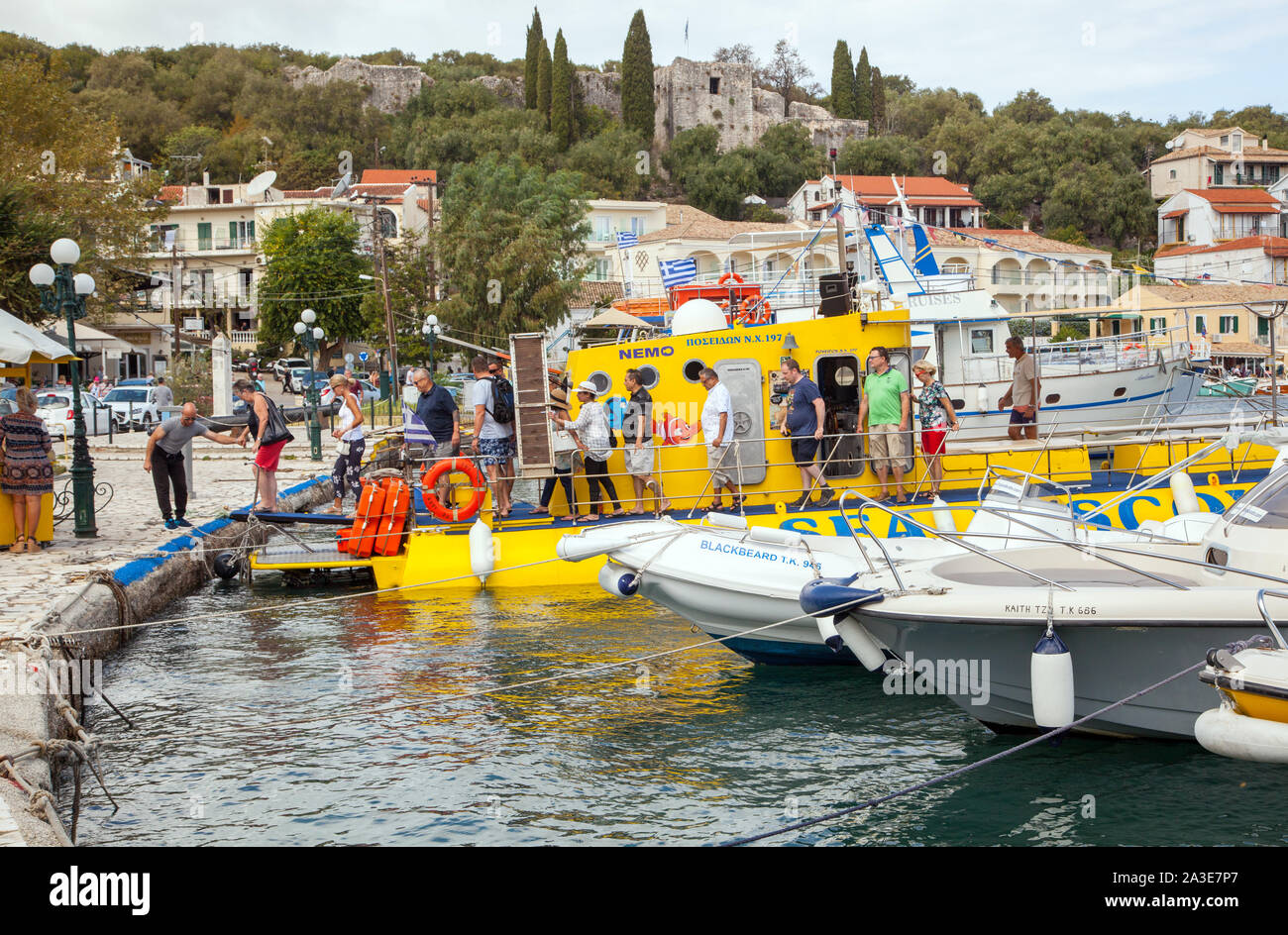 Le persone e i villeggianti scendere una gita in barca nel porto al Greek holiday resort di Kassiopi Corfù Grecia Foto Stock