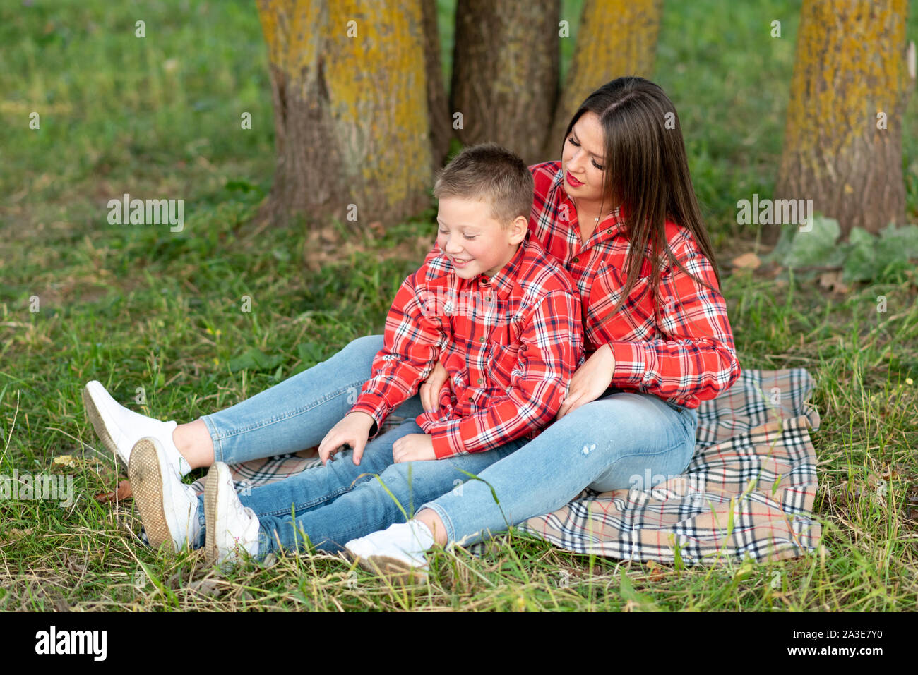 Madre e figlio seduti sul copriletto, parlare e sorridere. Foto Stock