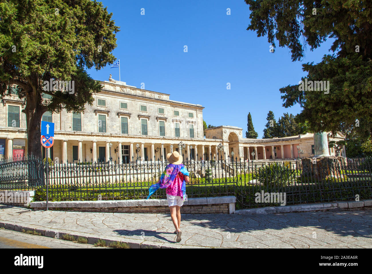 La donna nel cappello di paglia e sciarpa luminoso al di fuori del Palazzo Greco di San Michele e San Giorgio in bright sole estivo nella cittadina di Corfu Grecia Foto Stock