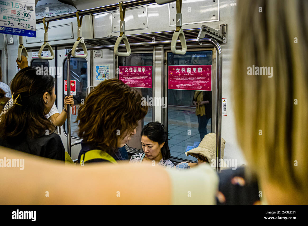 Donne si trovano ammassate nel vagone riservato alle sole donne della metropolitana di Tokyo, Giappone. Cartelli rossi con la scritta „Solo per donne“ segnalano il vagone riservato. Foto Stock