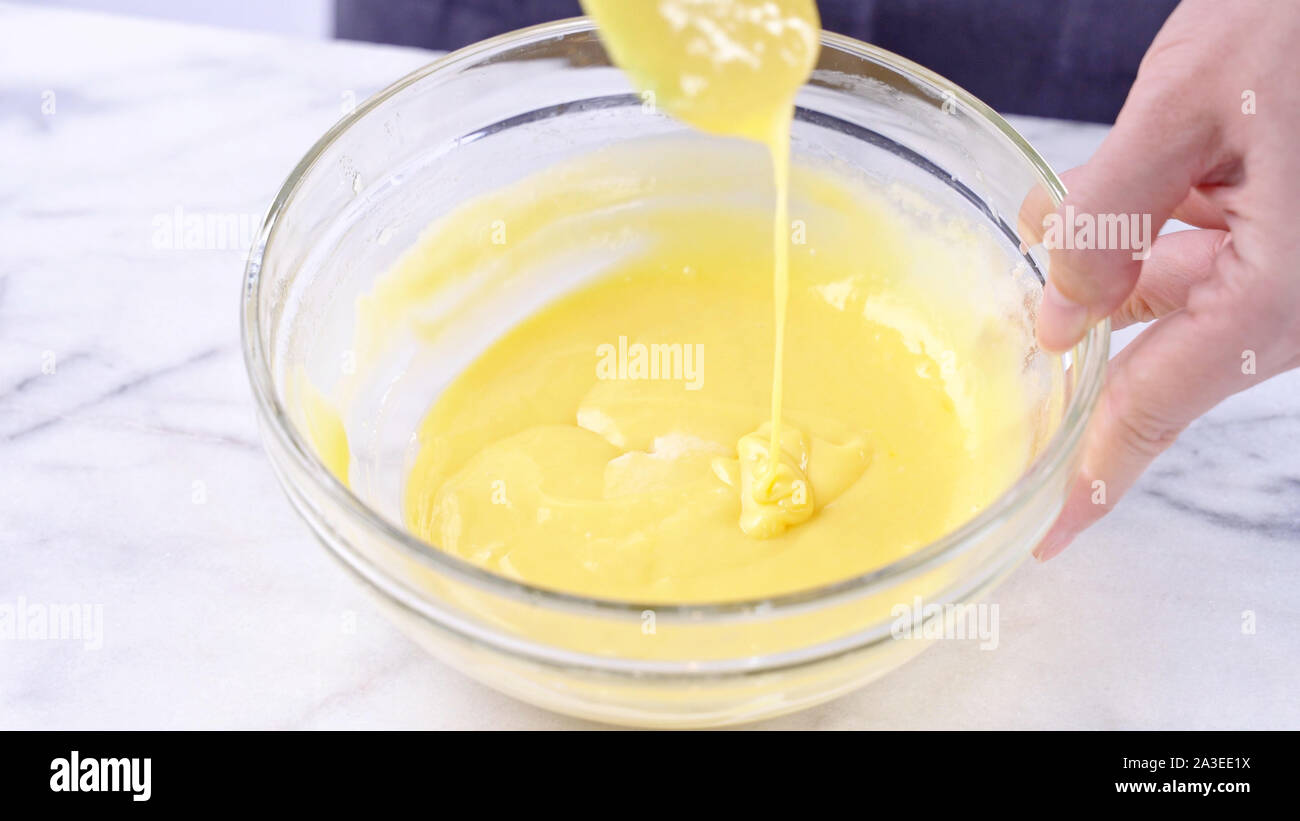 La miscelazione di tuorlo d'uovo nella torta verde con una spatola di gomma attrezzo miscelatore mescolando fino ad ottenere un composto omogeneo e frullare bene in una ciotola di vetro, close up, lo stile di vita Foto Stock