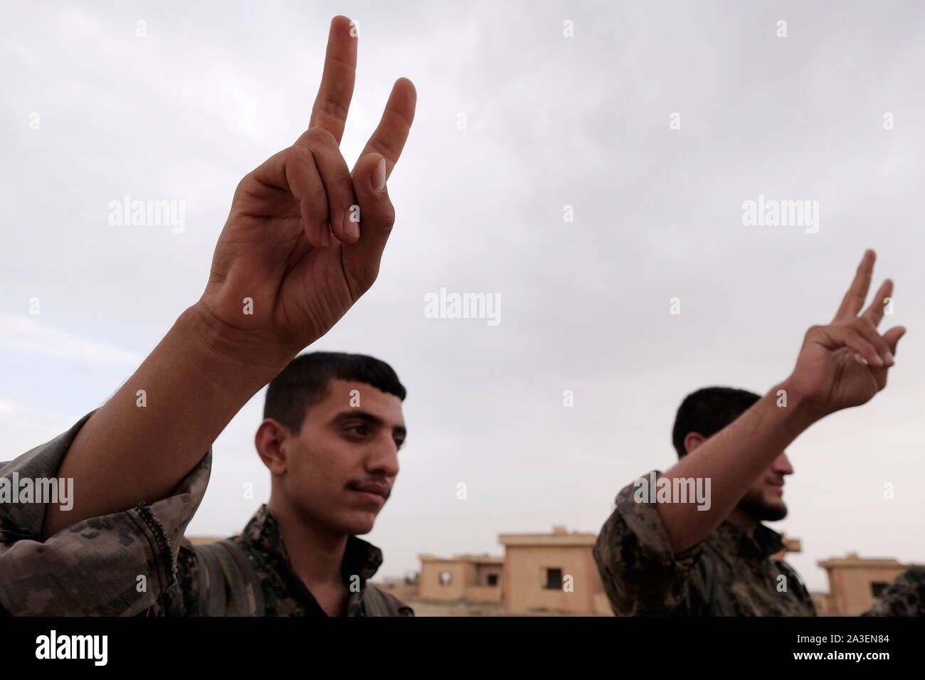 Combattenti curdi del popolo della unità di protezione YPG segnando il segno della vittoria durante una cerimonia di consegna dei diplomi in un accampamento di assunzione in Al Hasakah o distretto Hassakeh nella Siria settentrionale Foto Stock