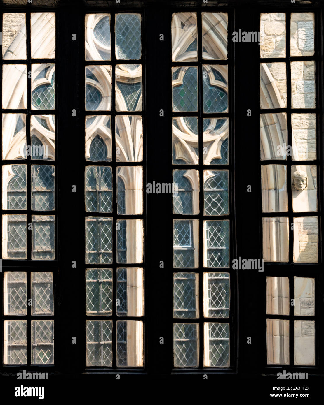 Vista guardando fuori attraverso vecchie finestre in vetro piombato di Leicester Guildhall in corrispondenza di una finestra della cattedrale di Leicester, Leicester, England, Regno Unito Foto Stock