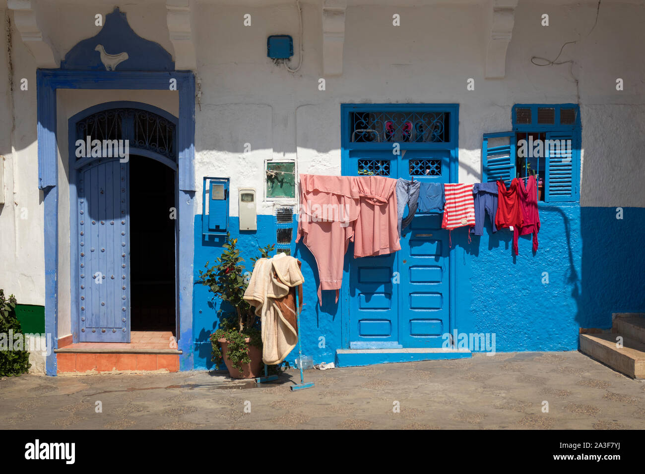 Facciata di una casa tradizionale con biancheria appesa all'aperto nella medina di Assilah, Marocco Foto Stock