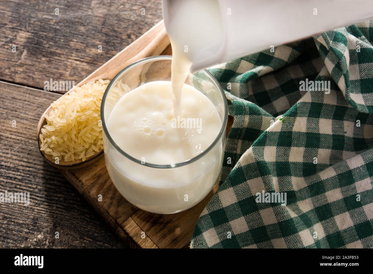 Versare il latte di riso in vetro su un tavolo di legno. Foto Stock