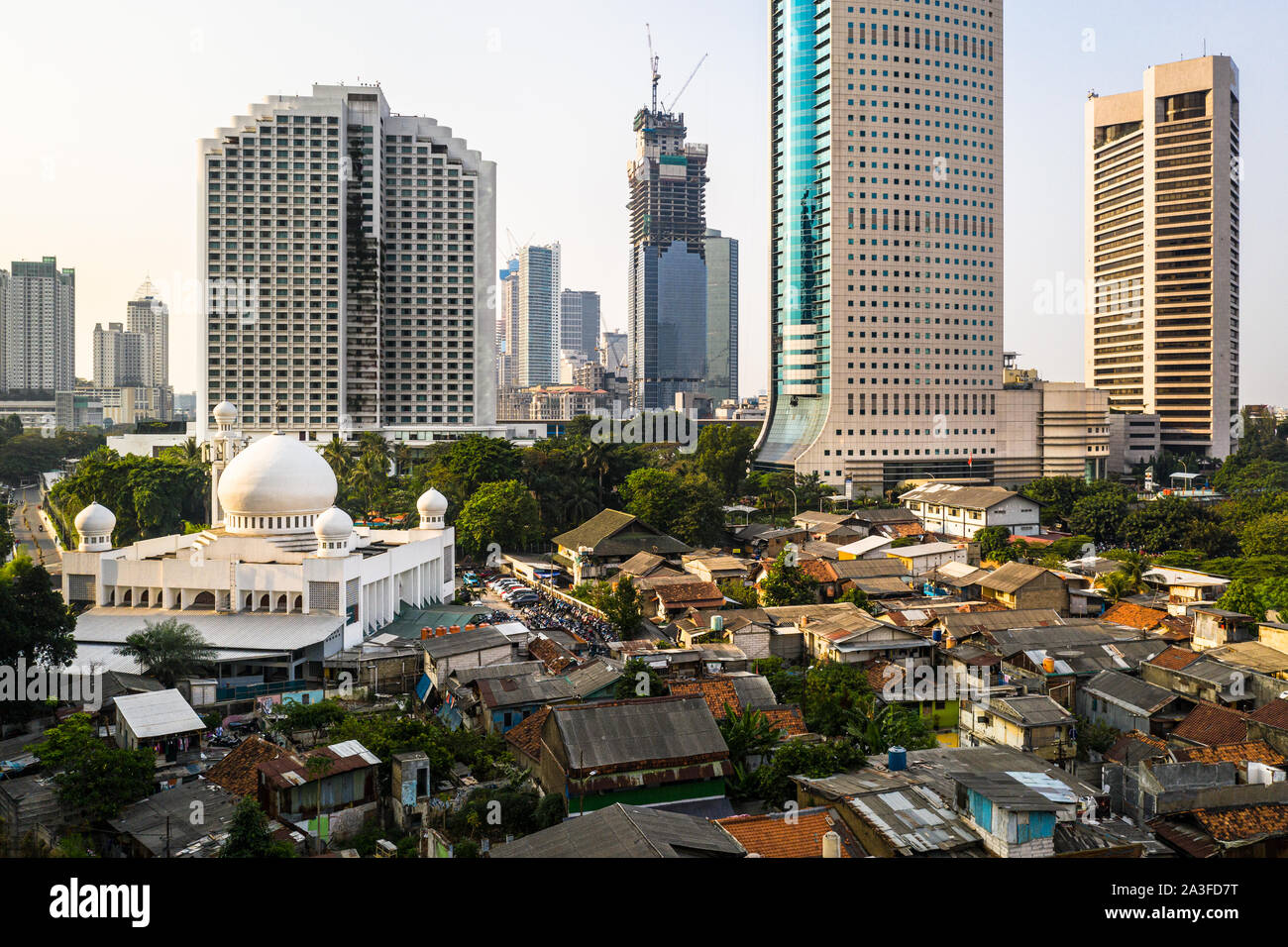Il contrasto in Jakarta centro distretto con i moderni grattacieli, una grande moschea e una molto affollato a basso reddito quartiere residenziale in Indonesia capitale Foto Stock