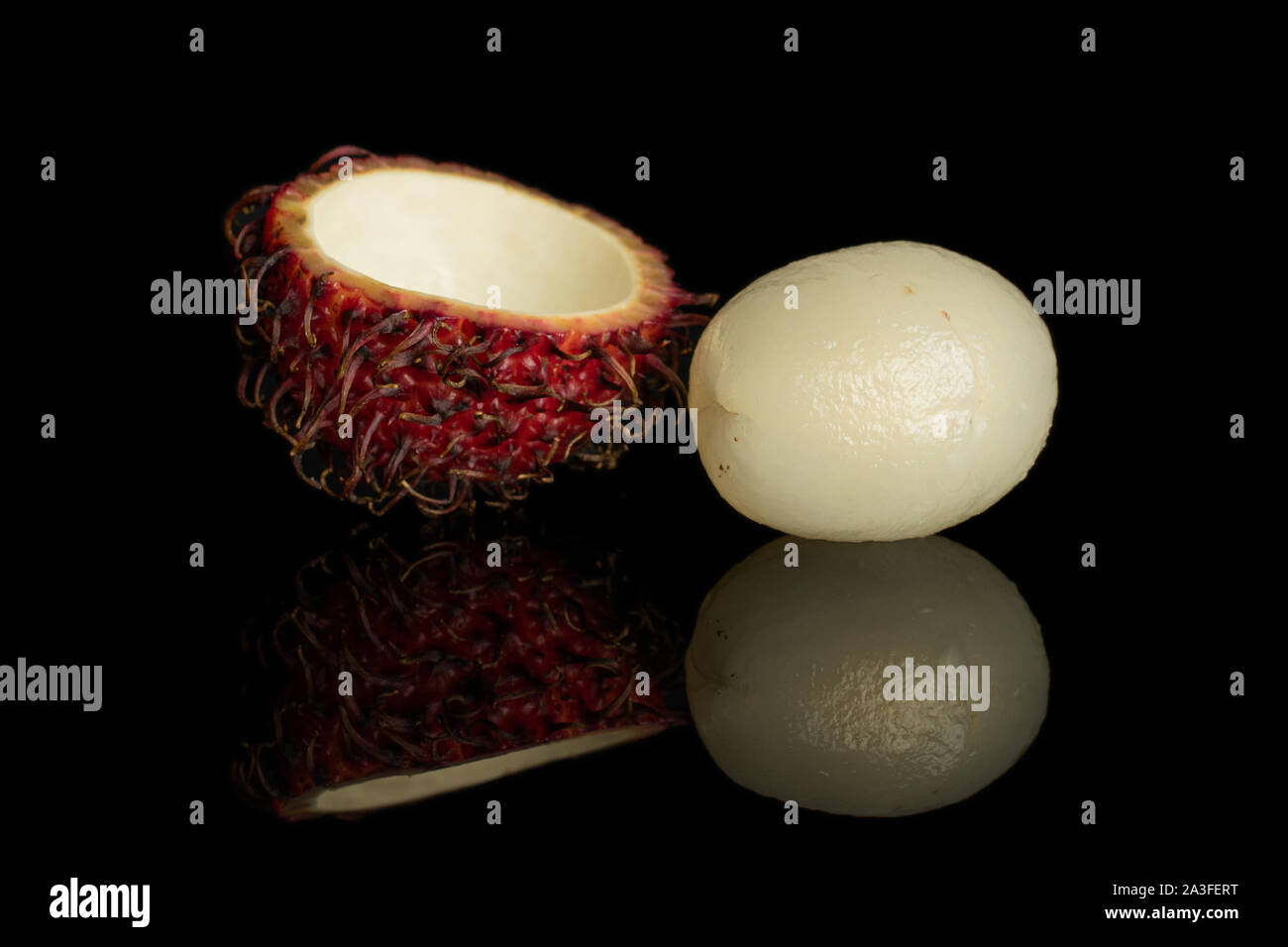 Gruppo di una intera metà del rosso fresco rambutan uno pelato isolato sul vetro nero Foto Stock
