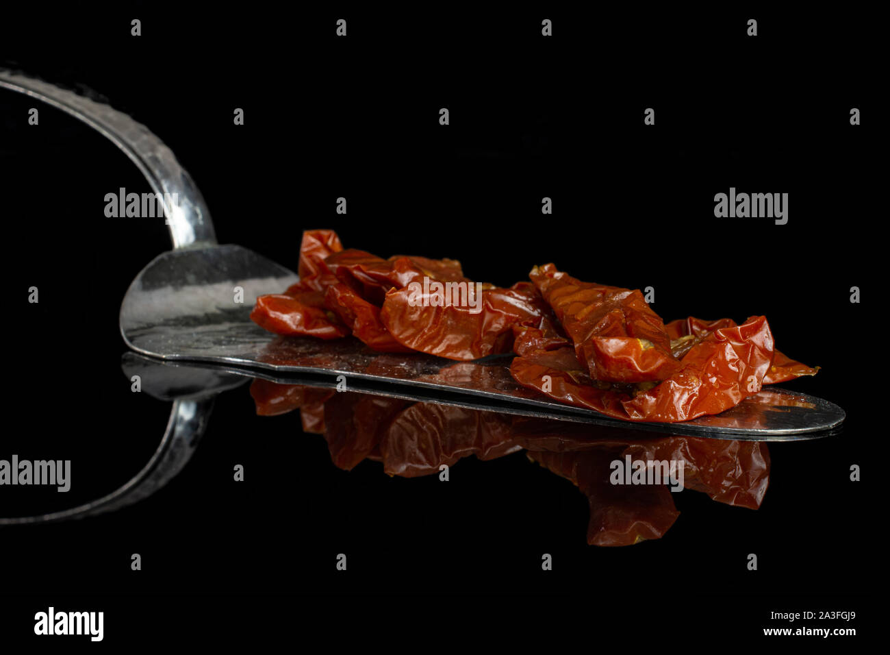 Sacco di fette di rosso secco pomodori ciliegia con torta spatola isolato sul vetro nero Foto Stock