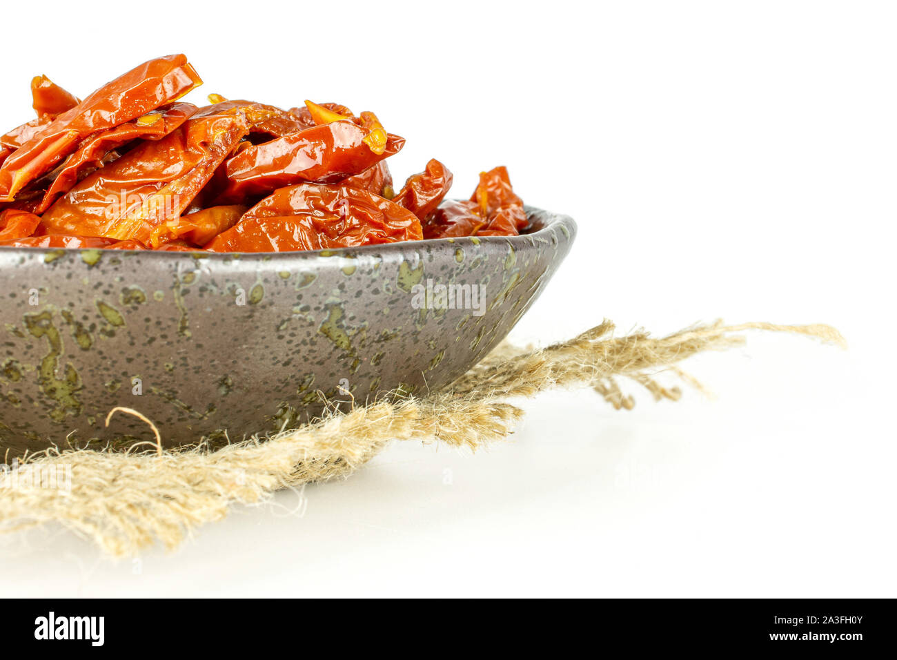 Sacco di fette di dry Red Cherry Pomodoro sul grigio piastra in ceramica sulla stoffa di iuta isolati su sfondo bianco Foto Stock