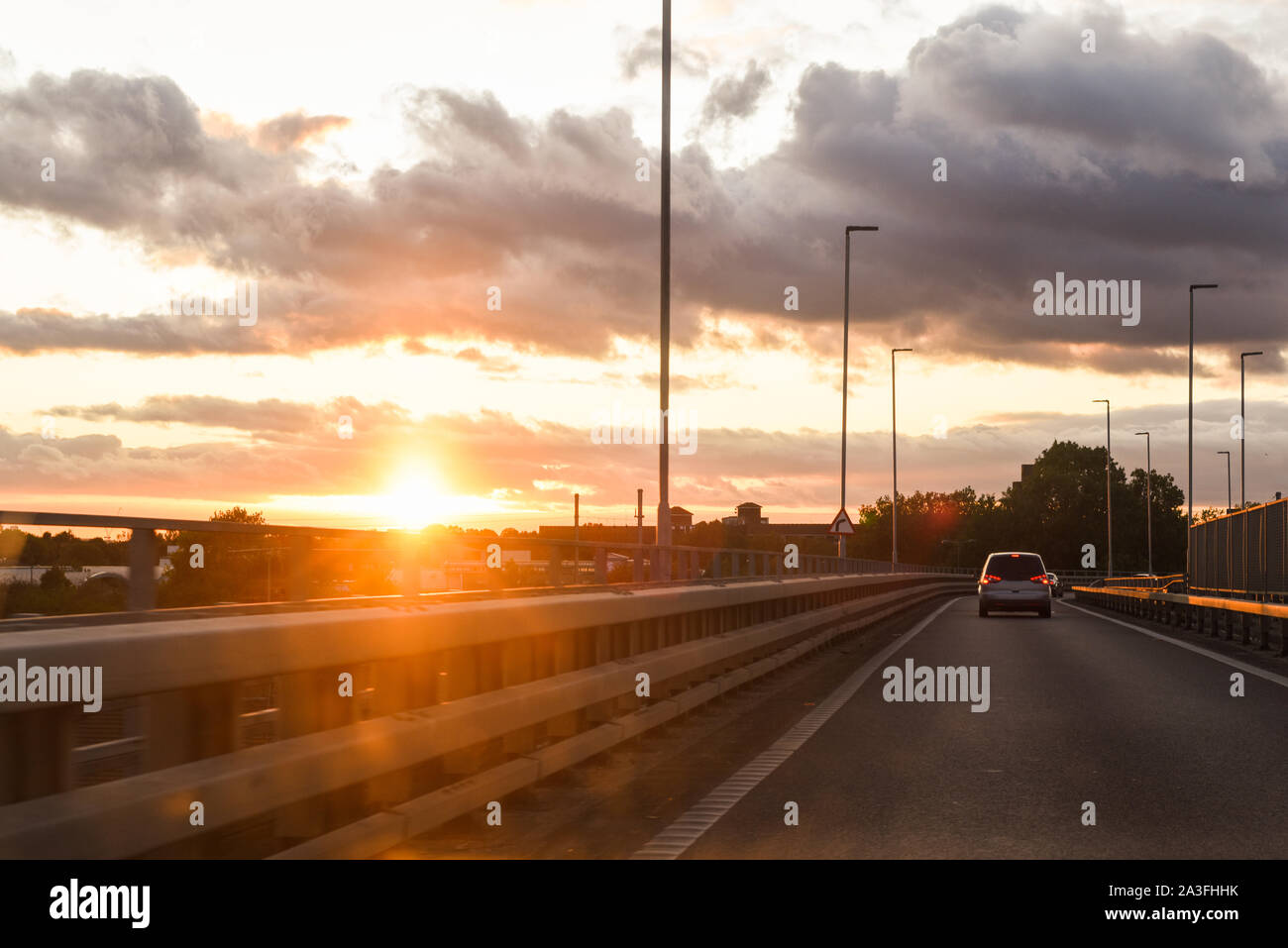 La guida al tramonto vista dall'interno del veicolo con traffico davanti Foto Stock