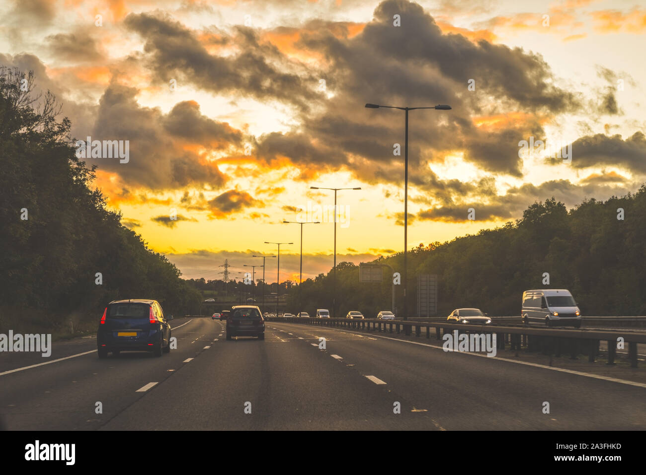 La guida al tramonto su una strada principale nella corsia centrale vista dall'interno di un automobile Foto Stock