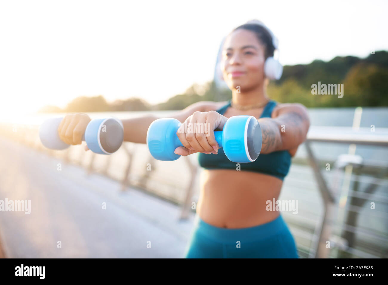 Donna blu holding barbells mentre la costruzione dei muscoli del braccio Foto Stock Donna blu holding barbells mentre la costruzione dei muscoli del braccio Foto Stock