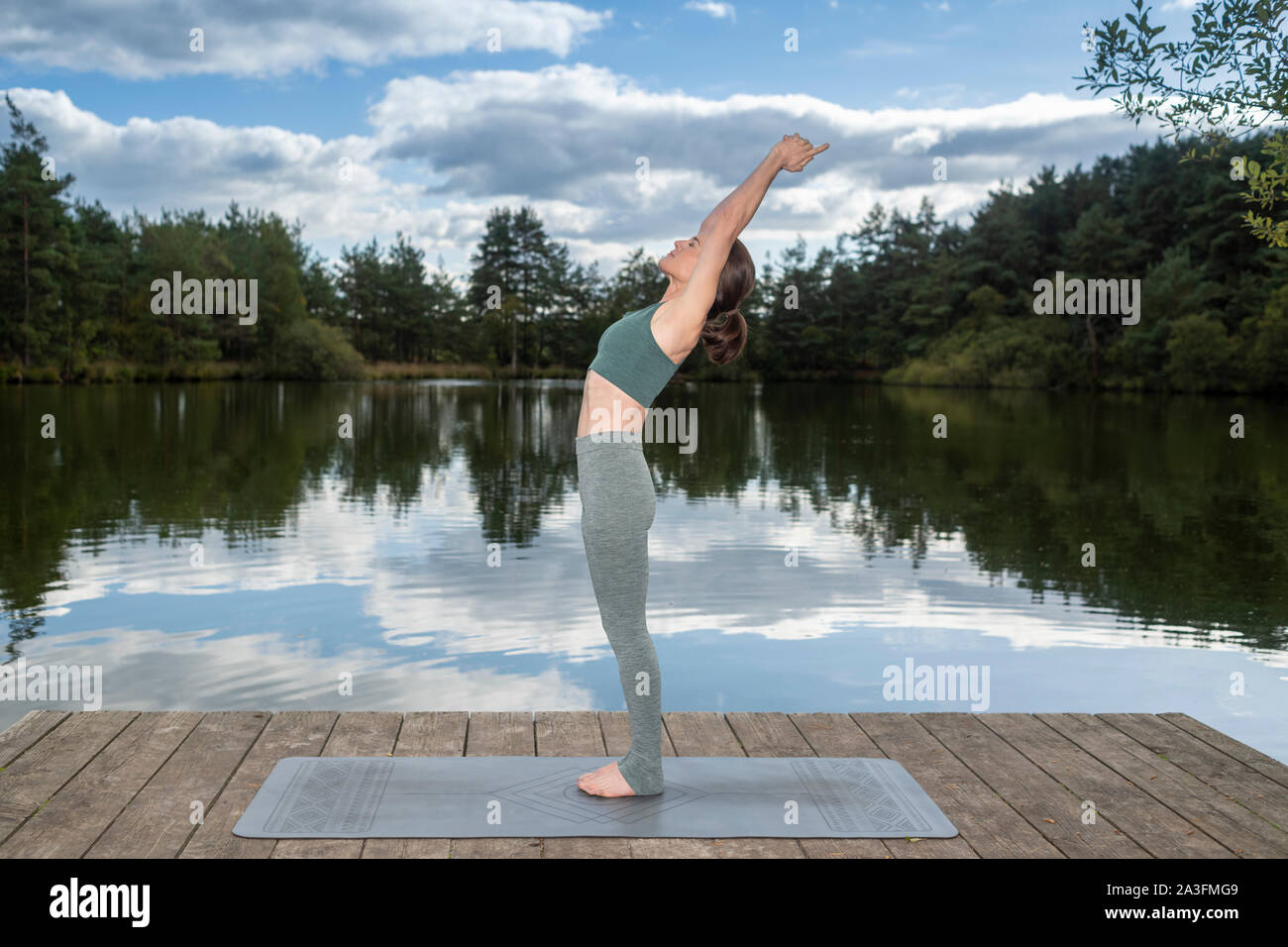 La donna a praticare yoga su un molo da un lago, montagna, Foto Stock