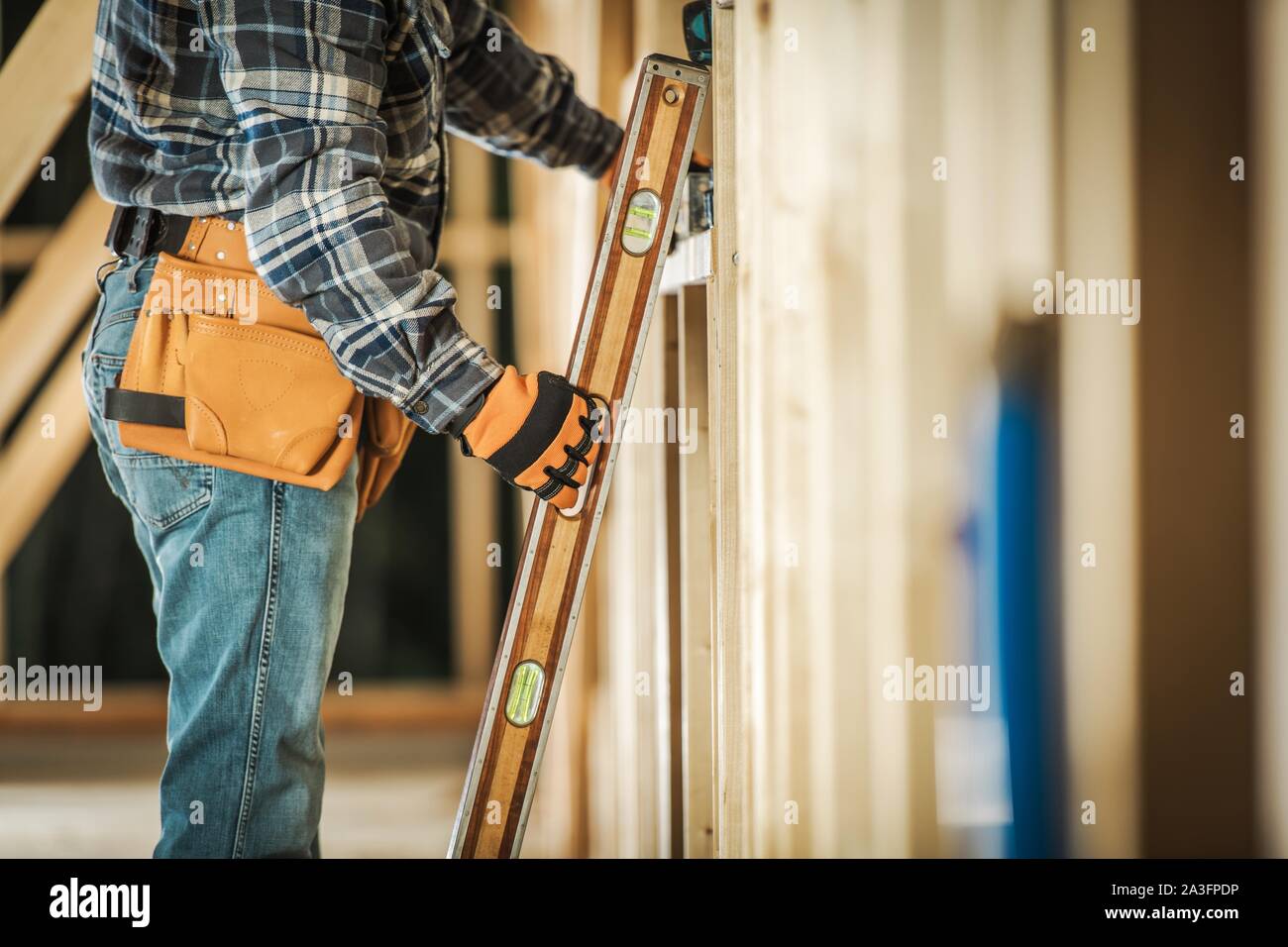 Lavoratore contraente tenendo la livella strumento per assicurarsi che la cornice in legno l'allineamento è corretto. Costruzione degli strumenti e delle tecnologie per l'edilizia. Foto Stock