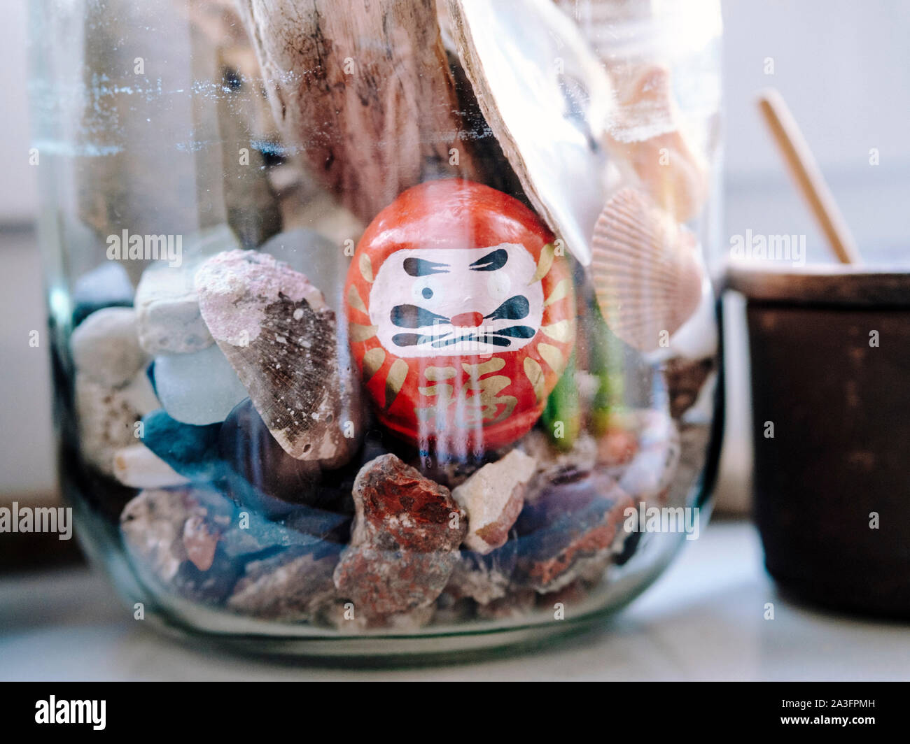 Home design: Ecosphere con giardino di pietra e giapponese Daruma doll Foto Stock