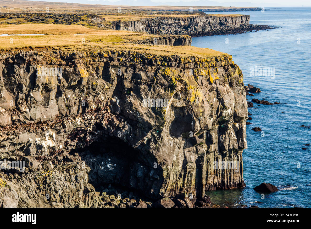 Il litorale lungo dalle rocce Londrangar mostrando le scogliere con colonne di basalto. Una giornata di sole sulla penisola di Snaefellsness West Islanda.. Foto Stock