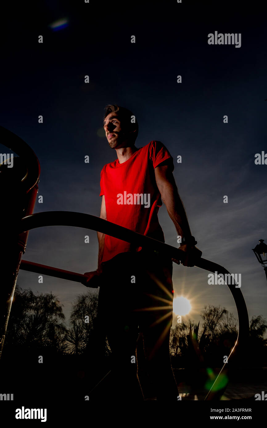 Atleta di eseguire esercizi su macchine poste su un lungomare accanto alla spiaggia al tramonto Foto Stock