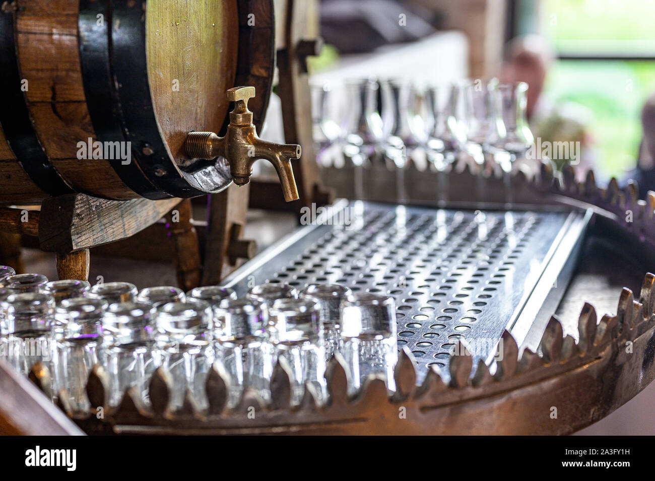 Vecchia botte di rovere con spirito di whiskey piccoli bicchieri su un tavolo di legno. davanti a sfondo sfocato partito impostazione della stazione. Foto Stock