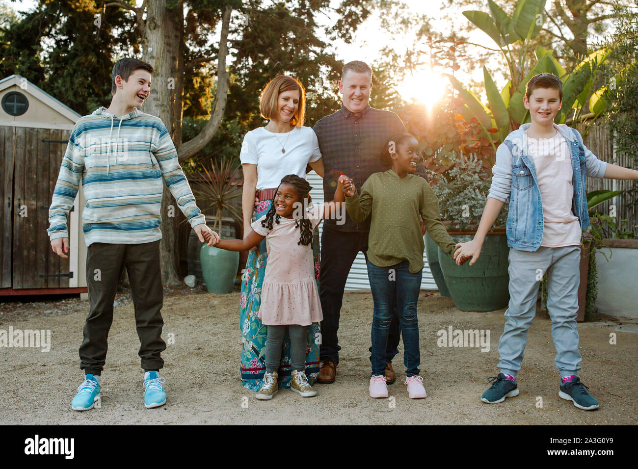 Felice di mixed-gara famiglia ridendo e tenendo le mani Foto Stock